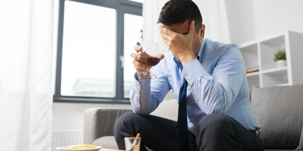 man drinking alcohol, head in hands