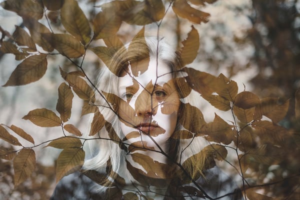 girl looking through tree leaves