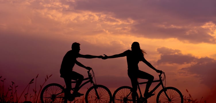 couple holding hands while bike riding