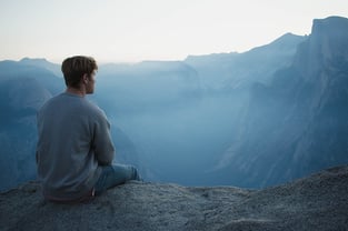 man sitting on the edge of a cliff